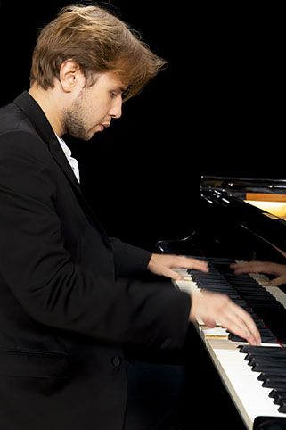 Nikita viewed from side playing a grand piano